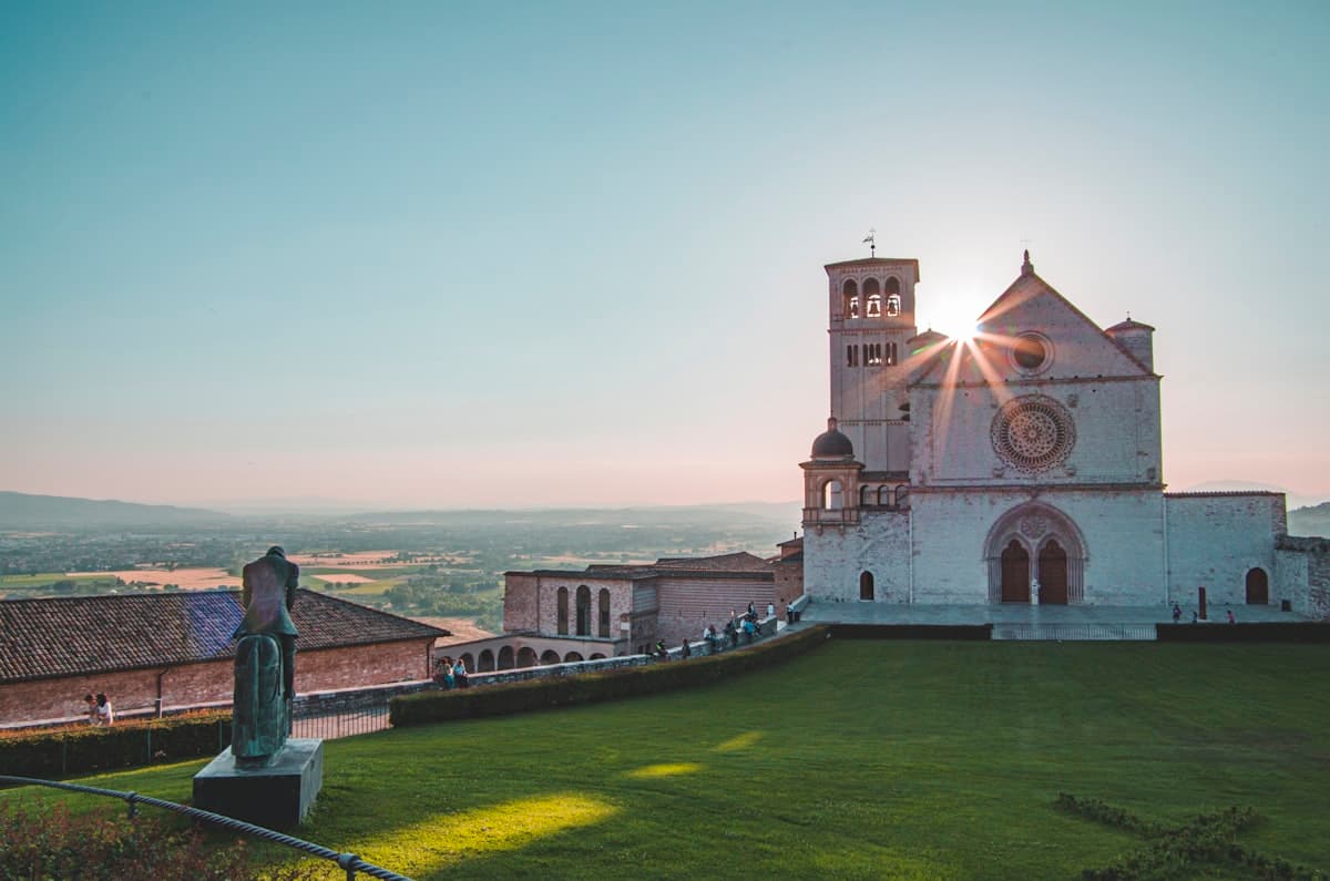Basilica of San Francesco d'Assisi at golden hour with the Umbrian valley beyond